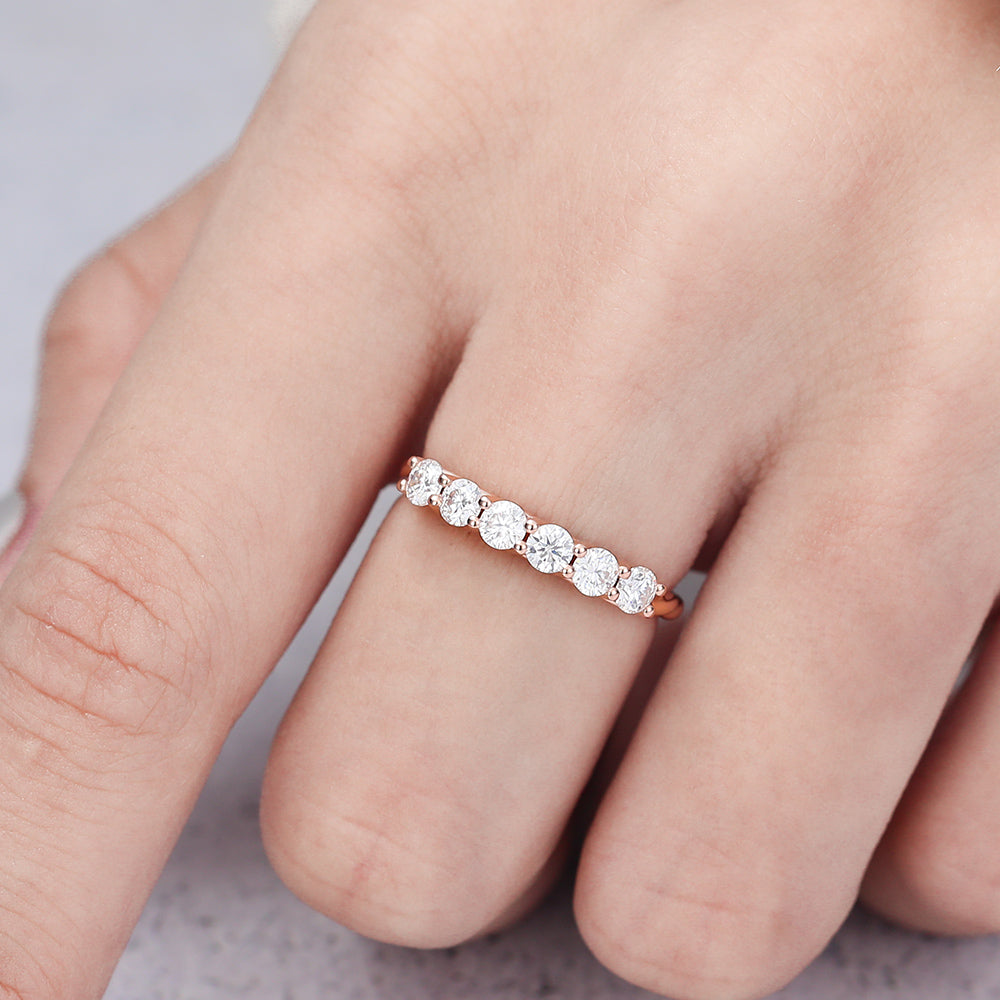 Rose gold six stone round moissanite half eternity band worn on a finger