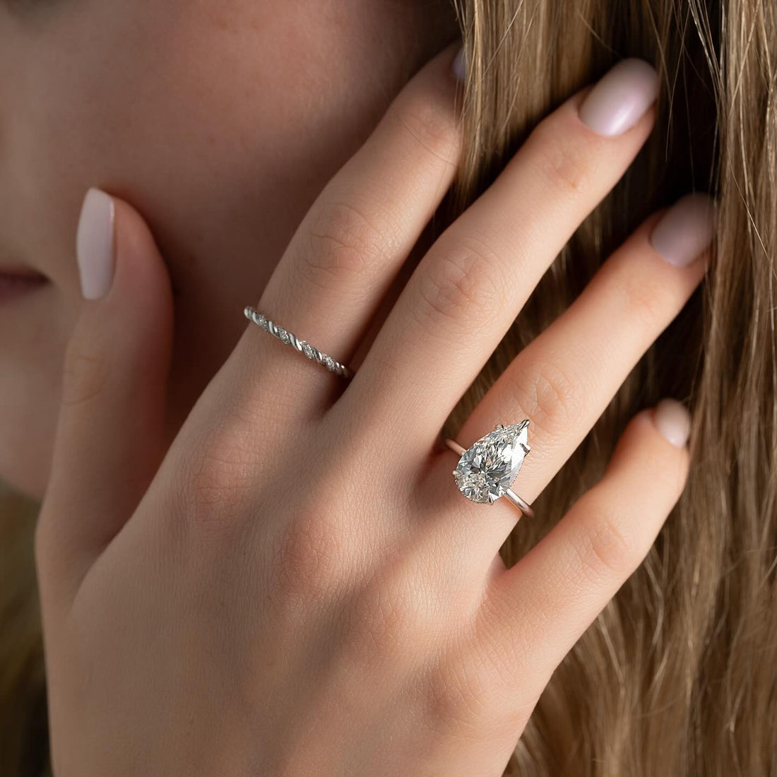 East west pear cut lab grown diamond ring on a plain white gold band worn on hand