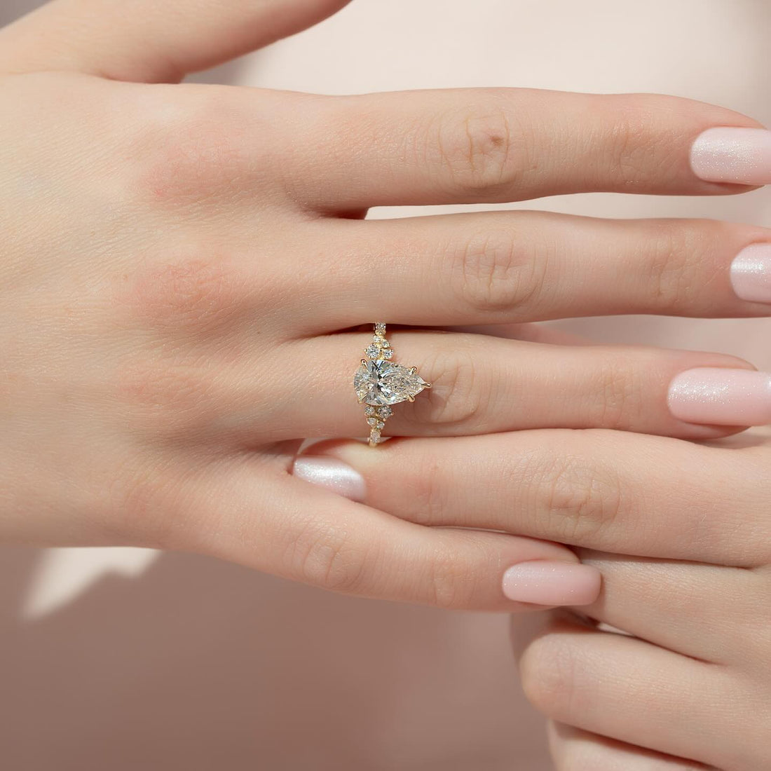 Pear cut lab grown diamond ring with scattered accent clusters in yellow gold worn on the hand