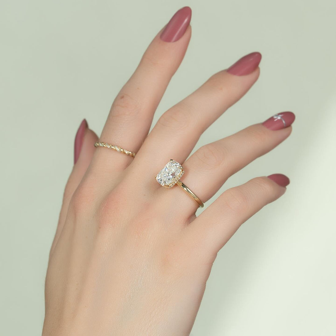 Elongated cushion cut lab grown diamond hidden halo ring in yellow gold worn on the hand