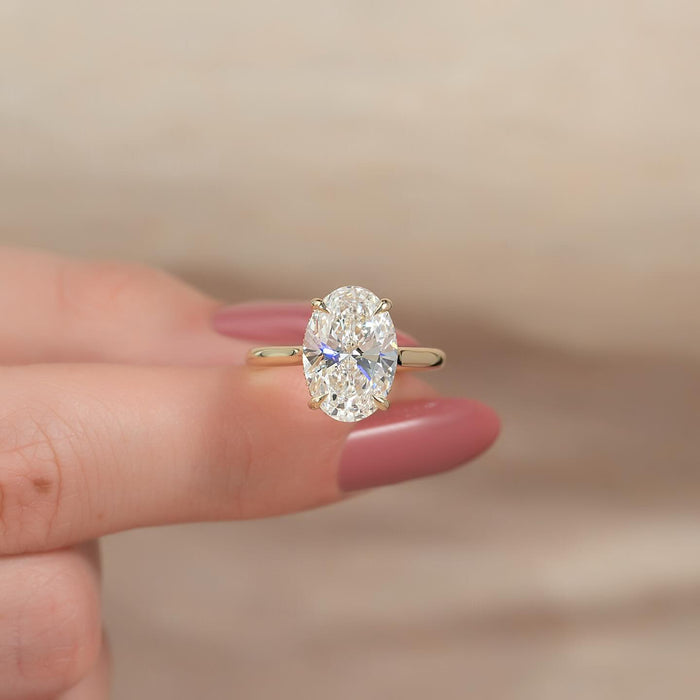Oval cut lab grown diamond hidden halo ring on a knife edge yellow gold band