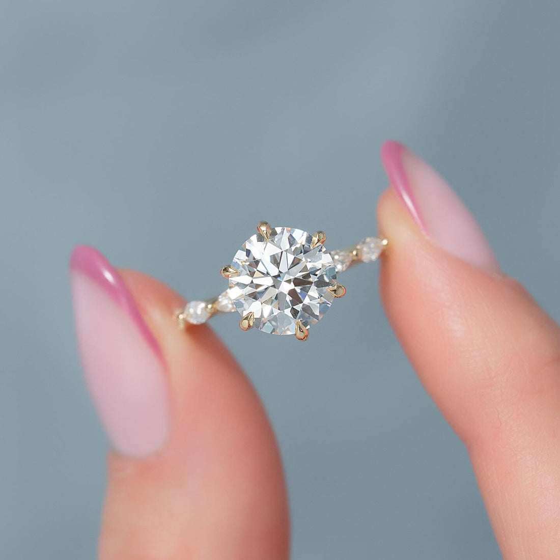 Round cut lab grown diamond eight claw ring with marquise accent band in yellow gold