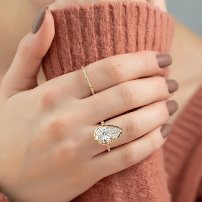 Full bezel rim wrapping the outline and point of the pear diamond