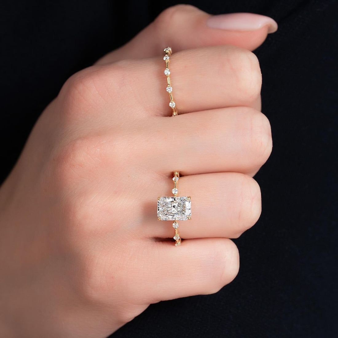 East west radiant cut lab grown diamond ring in yellow gold worn on the hand