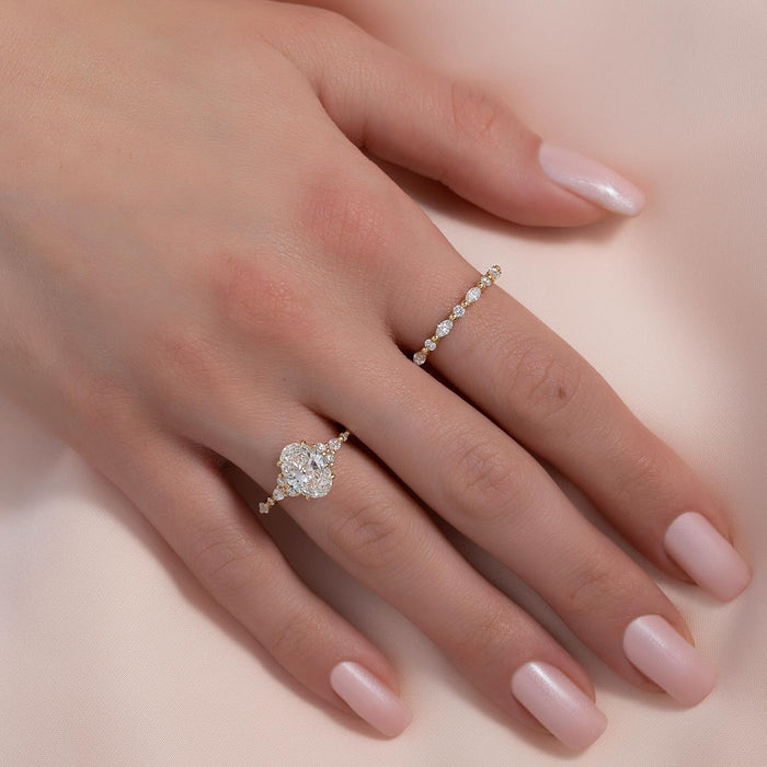 Oval cut lab grown diamond ring with graduated cluster shoulders in yellow gold worn on the hand