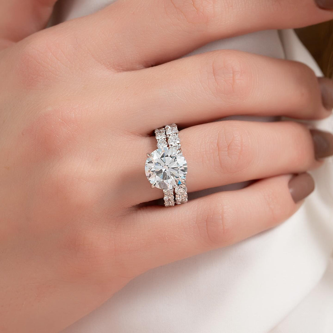 Round cut lab grown diamond bridal ring set with eternity band shank worn on the hand