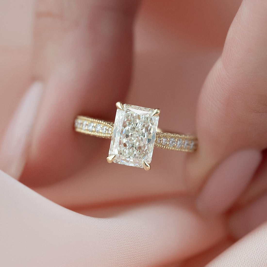 Radiant cut lab grown diamond ring on a milgrain framed pave yellow gold band