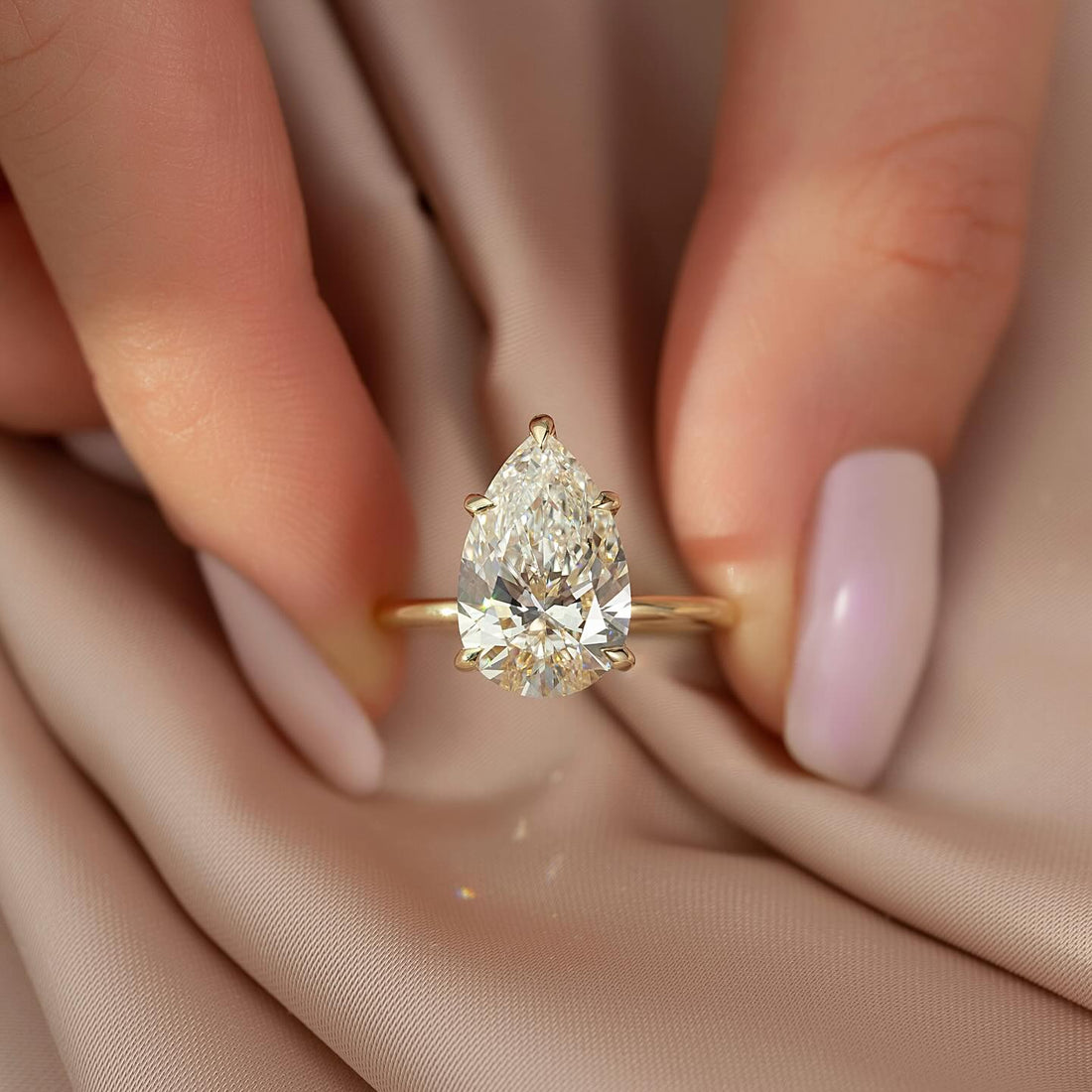 Pear cut lab grown diamond solitaire ring on a slim plain yellow gold band