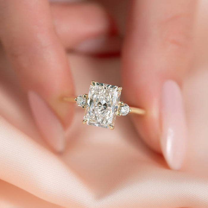 Radiant cut lab grown diamond ring with petite round accents on a thin yellow gold band