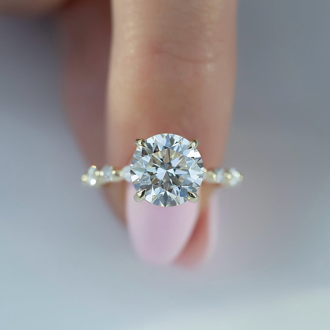 Round brilliant cut lab grown diamond ring with paired accent clusters in yellow gold