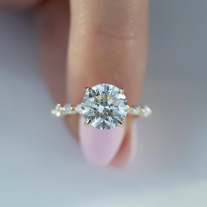 Round brilliant cut lab grown diamond ring with paired accent clusters in yellow gold