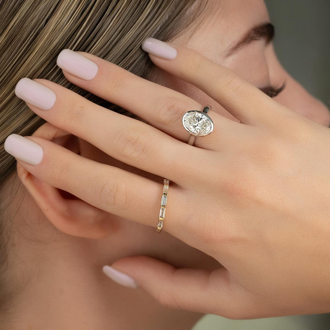 Oval cut lab grown diamond ring in a full bezel setting worn on hand