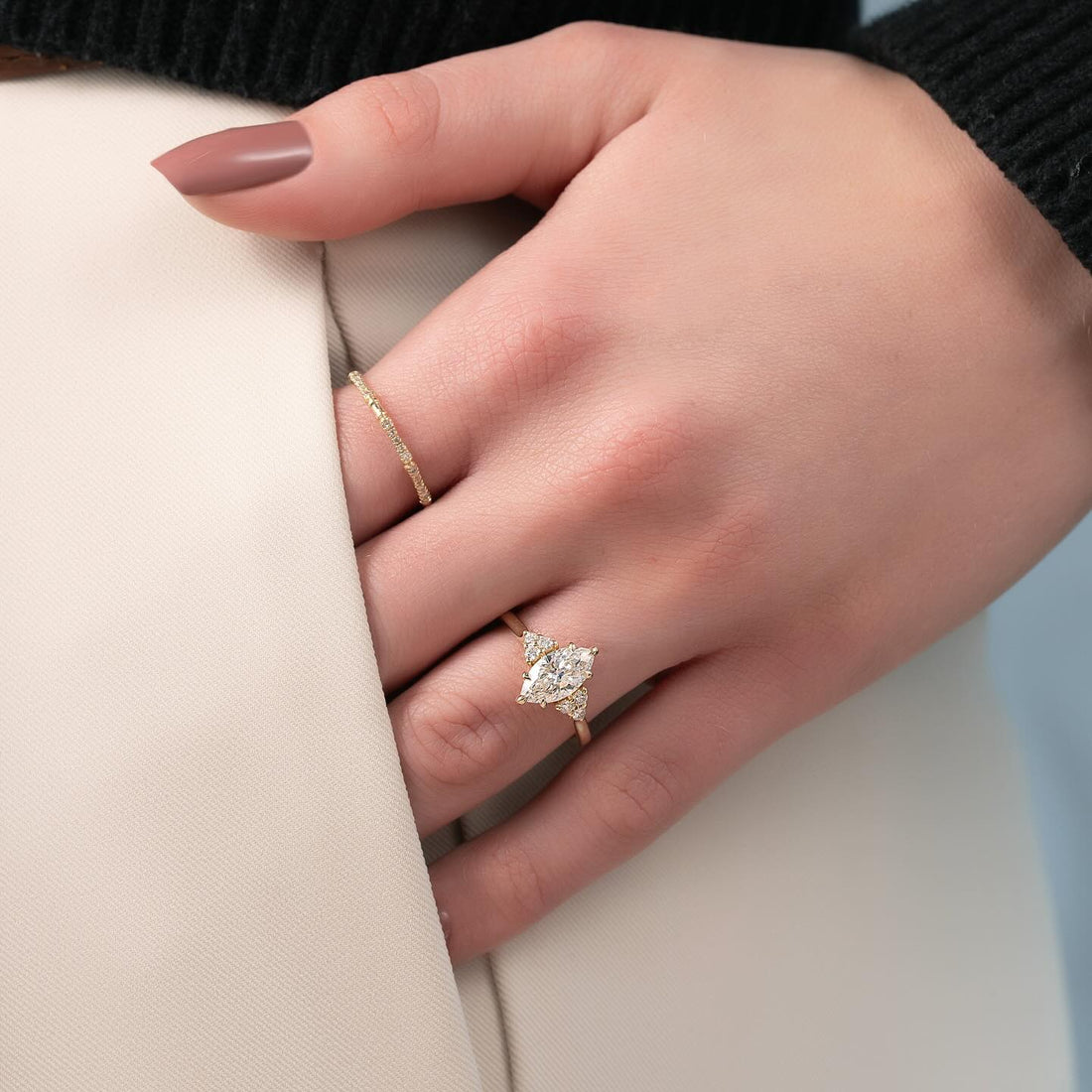 Marquise cut lab grown diamond ring with round accent clusters in yellow gold worn on the hand