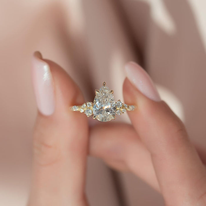 Pear cut lab grown diamond with round accent clusters on the shoulders