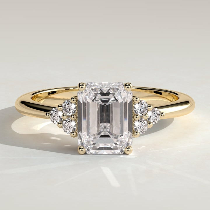 Emerald cut lab grown diamond ring with accent trios at the shoulders in yellow gold