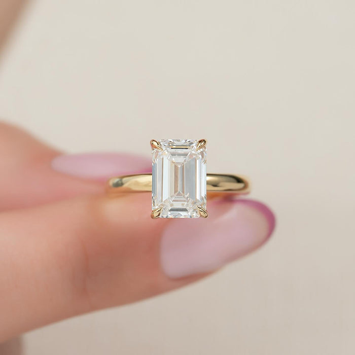 Emerald cut lab grown diamond four claw ring on a domed yellow gold band, front view