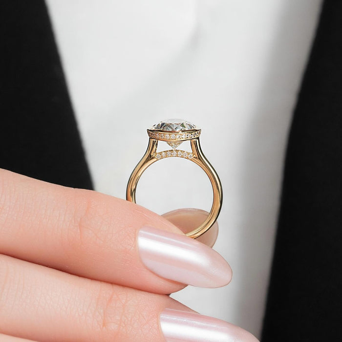 Full bezel rim around the oval diamond set sideways across the finger