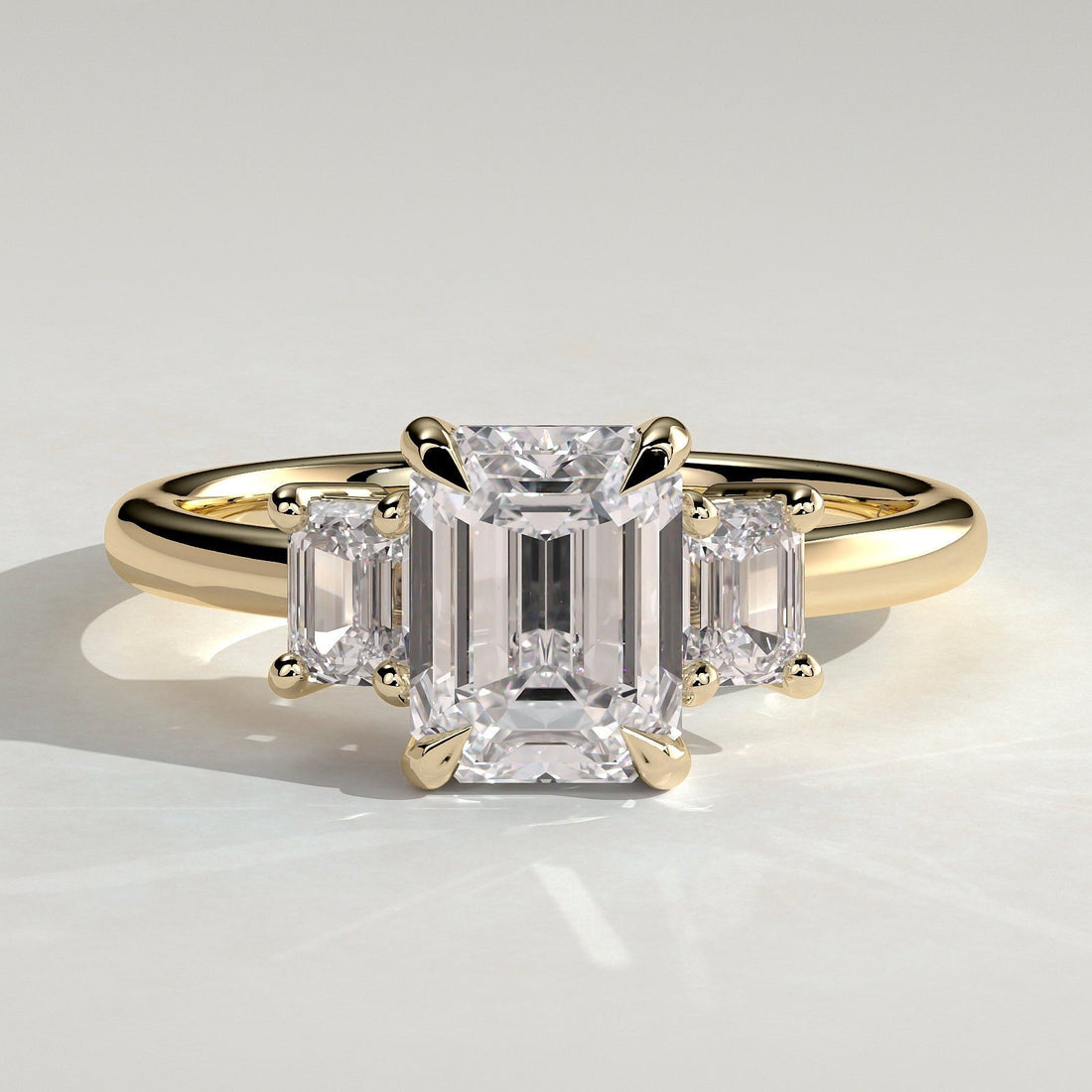 Emerald cut lab grown diamond three stone ring in yellow gold
