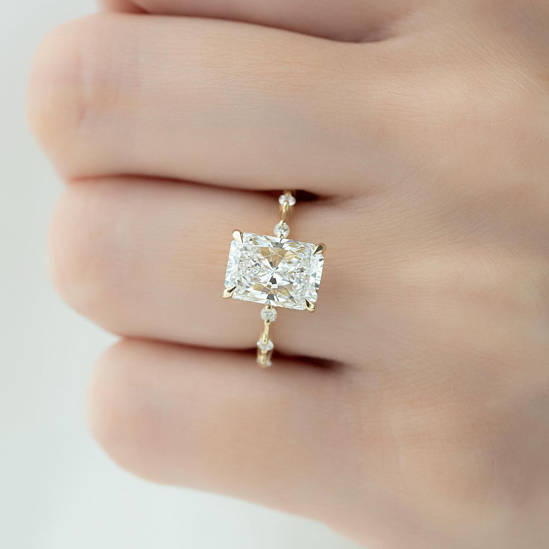 Radiant cut lab grown diamond ring with floating accents on a wire thin yellow gold band