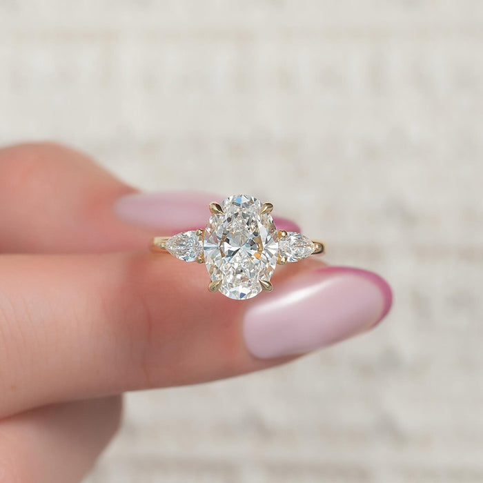 Oval cut lab grown diamond three stone ring with pear side stones in yellow gold, front view