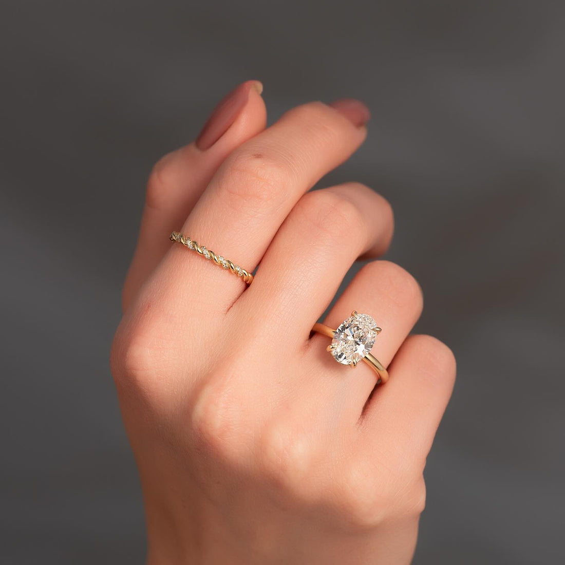 Oval cut lab grown diamond ring with wrapped hidden halo in yellow gold worn on the hand