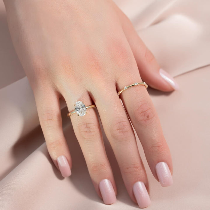 Oval cut lab grown diamond solitaire with plain polished yellow gold band worn on the hand