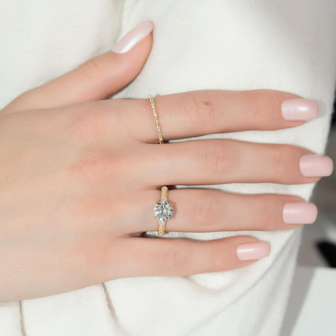 Round cut lab grown diamond ring with textured milgrain band in yellow gold worn on the hand