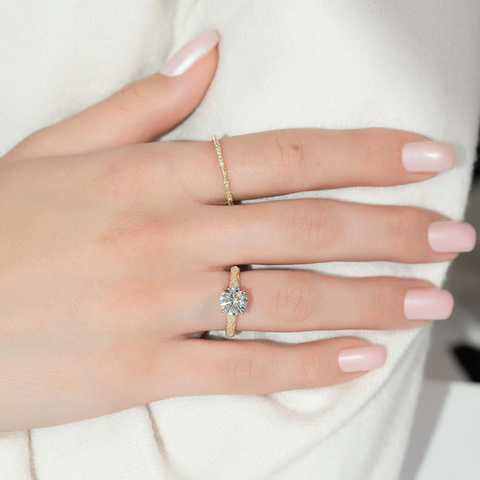 Round cut lab grown diamond ring with textured milgrain band in yellow gold worn on the hand