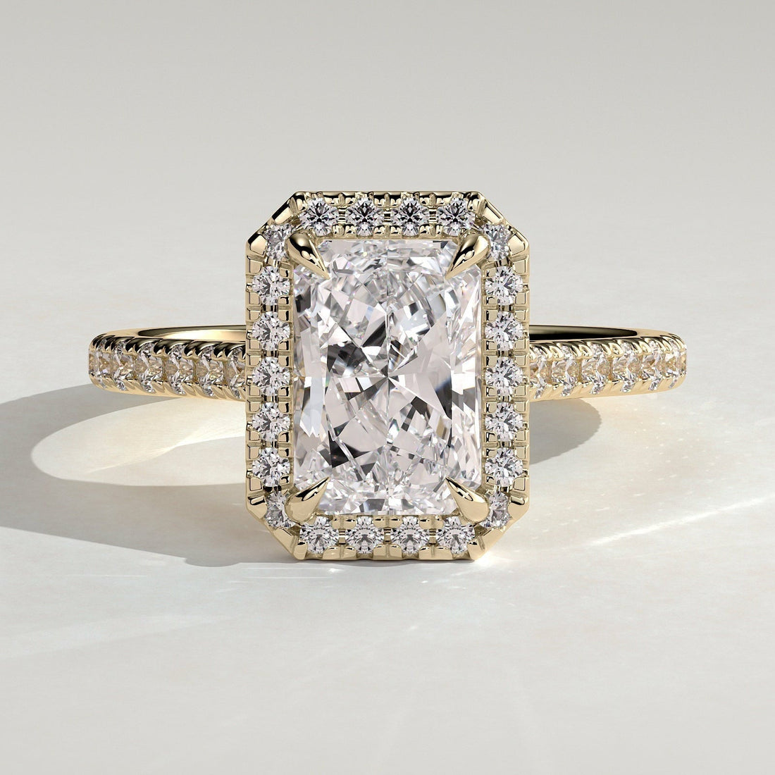 Radiant cut lab grown diamond halo ring on a pave band in yellow gold