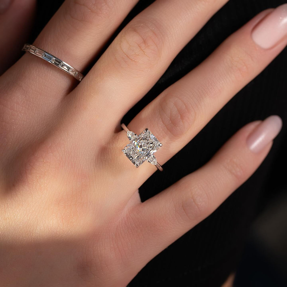 Radiant cut lab grown diamond ring with angled pear side accents in white gold worn on the hand
