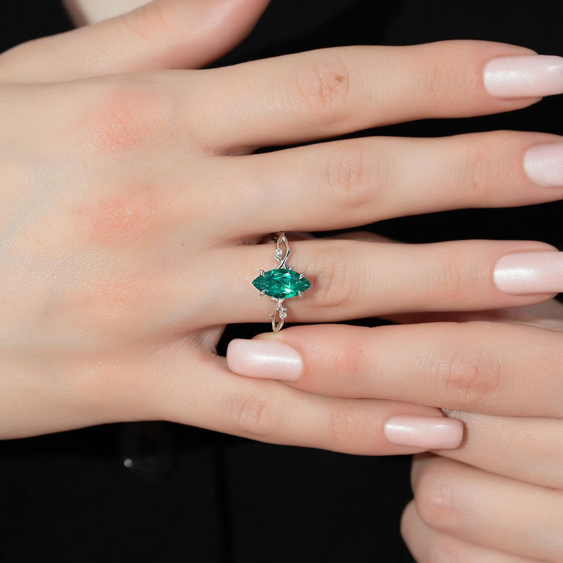 Marquise cut lab grown emerald ring with twisted vine band in white metal worn on the hand