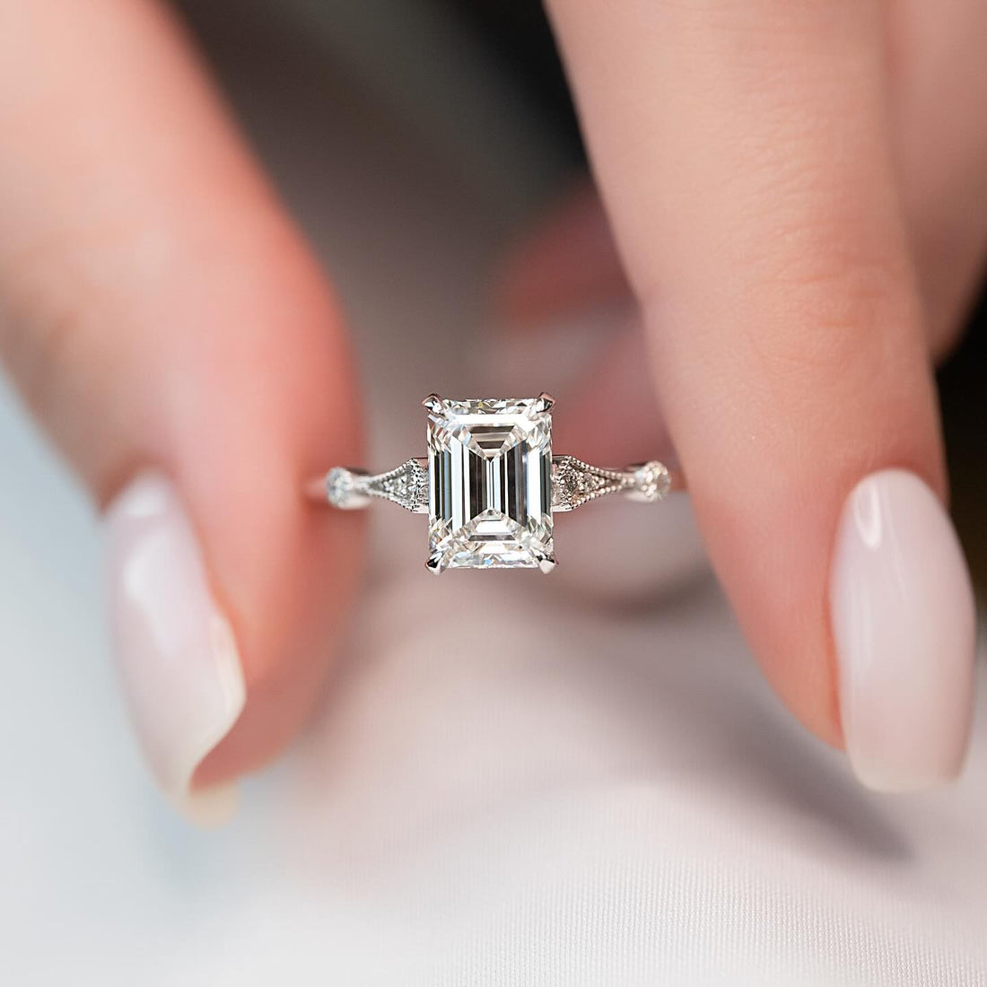 Emerald cut lab grown diamond ring in white gold with pinched milgrain fan shoulders