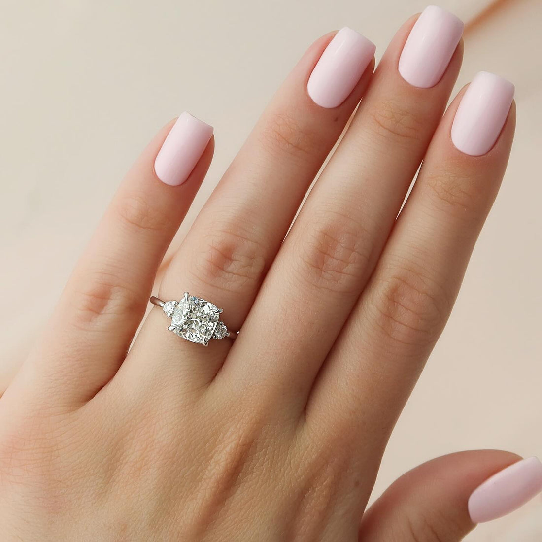 Cushion cut lab grown diamond three stone ring in white gold worn on hand