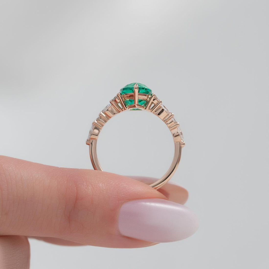 Pear cut lab grown emerald ring with diamond cluster sides in rose gold, front view