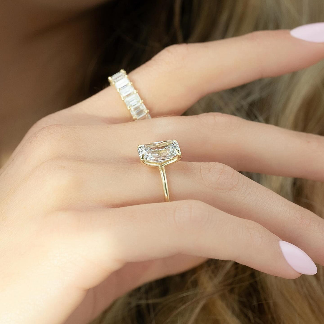 Elongated radiant cut lab grown diamond solitaire ring in yellow gold worn on the hand