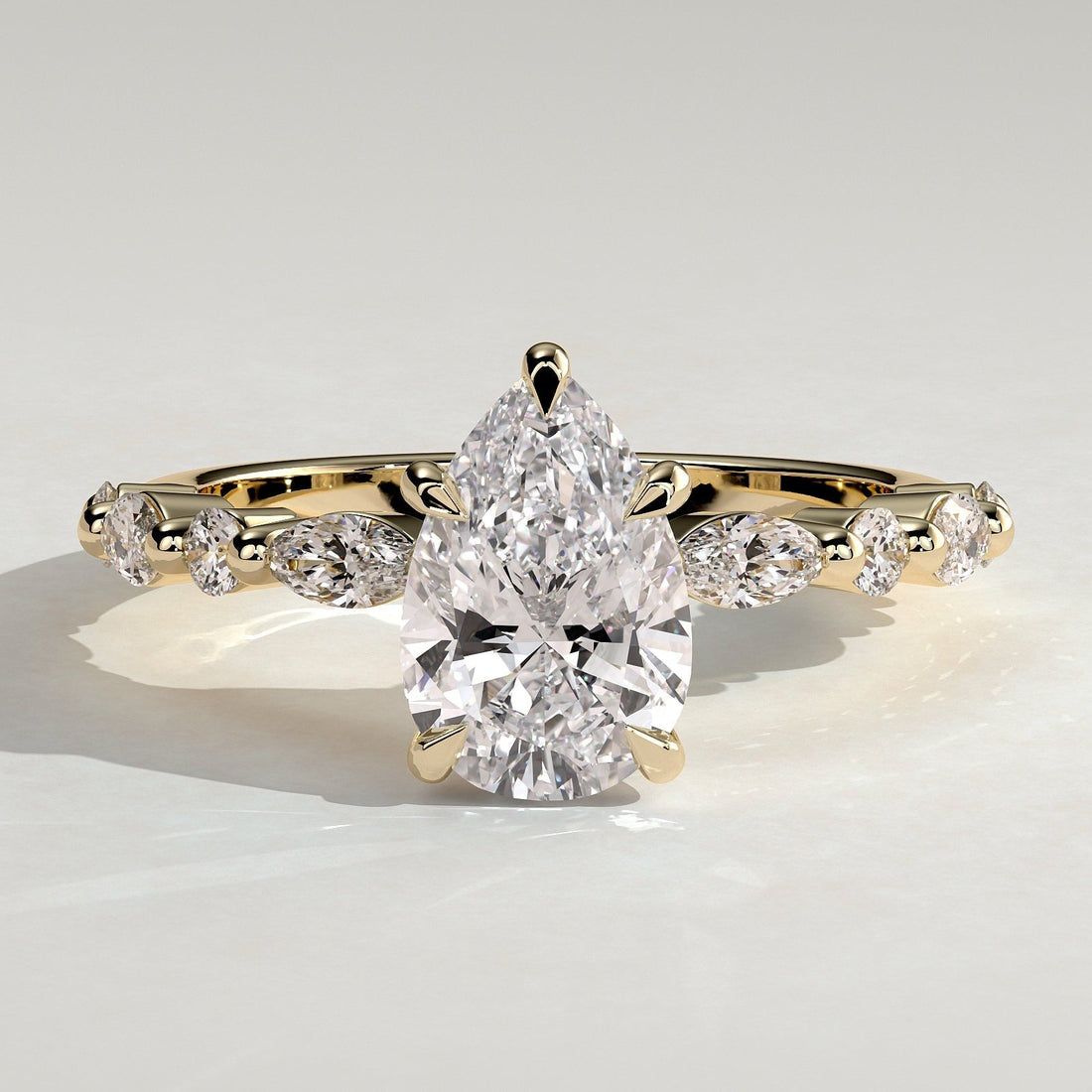 Pear cut lab grown diamond ring on an alternating accent band in yellow gold