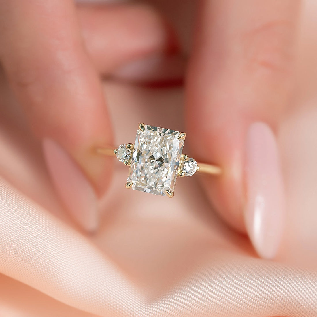 Radiant cut lab grown diamond three stone ring with round side diamonds in yellow gold