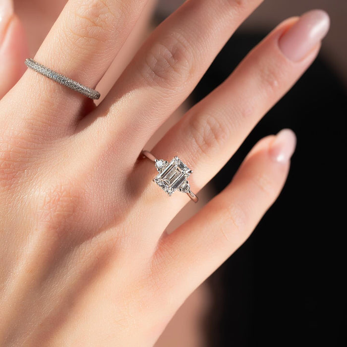 Emerald cut lab grown diamond ring with round corner accents in white gold worn on the hand