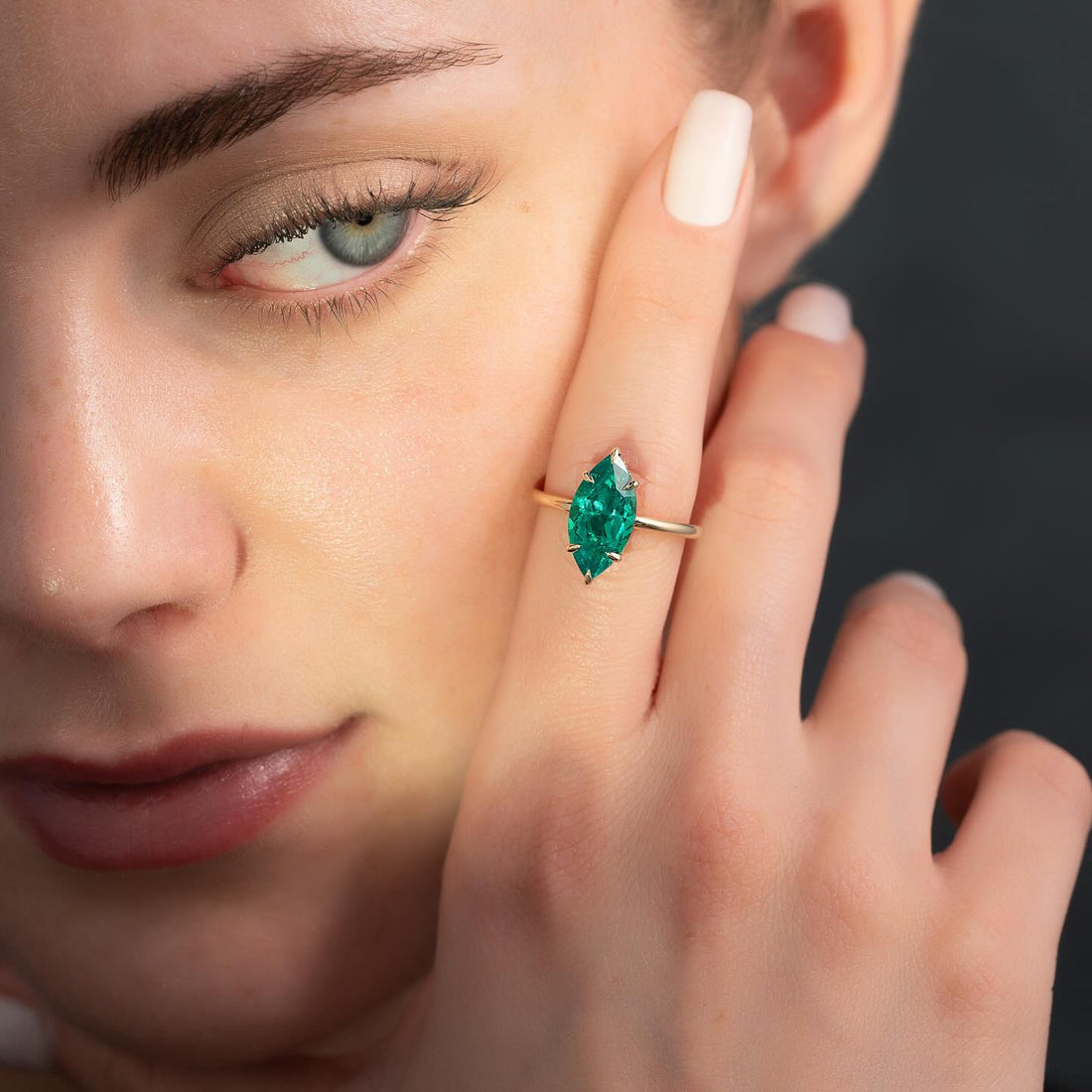 Marquise cut lab grown emerald solitaire ring in yellow gold worn on the hand