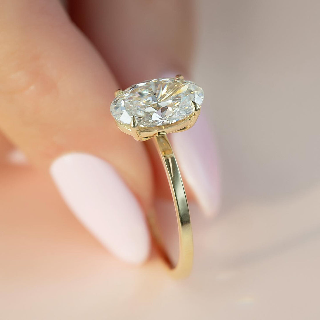 Oval cut lab grown diamond solitaire ring in yellow gold with four claws and a slim round band