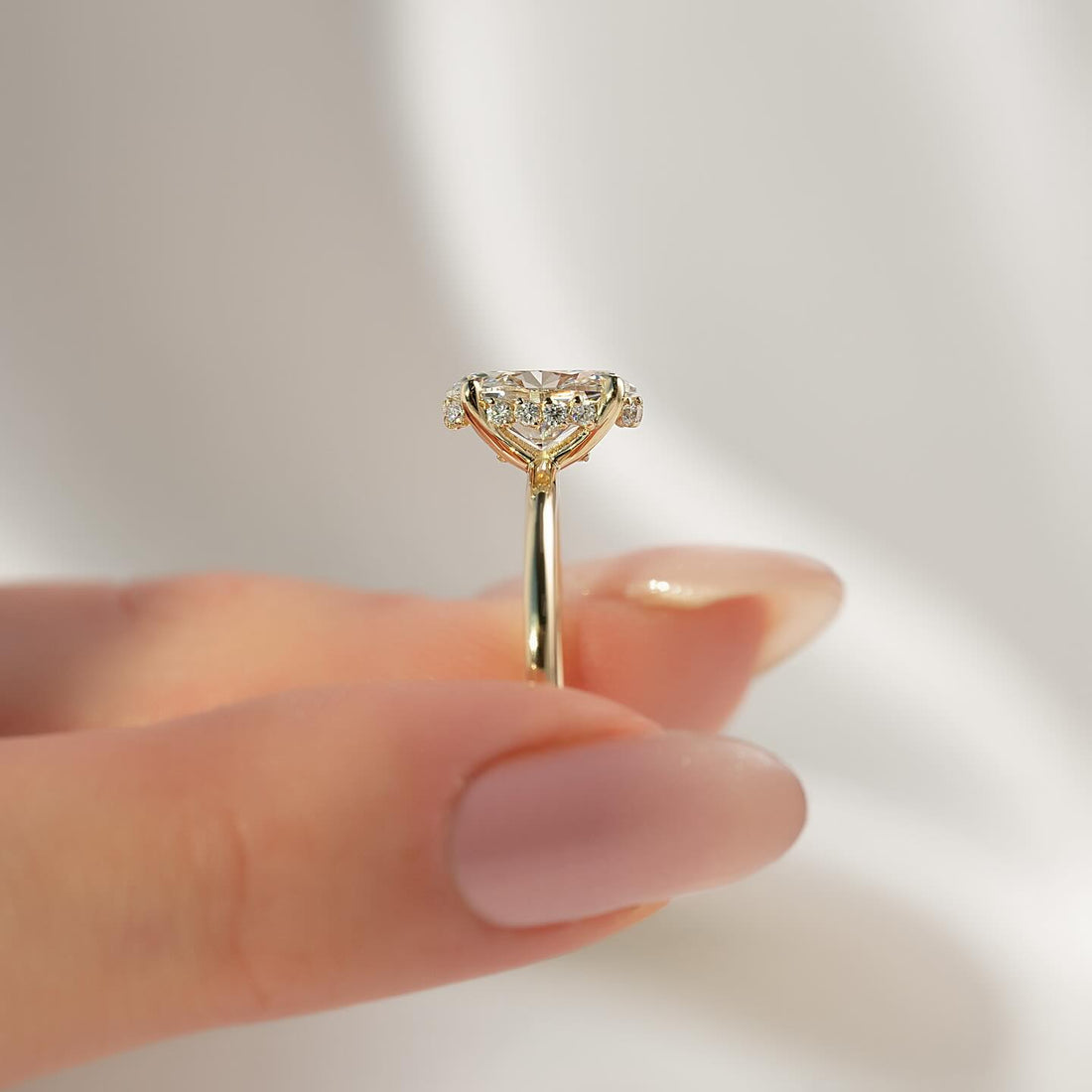 Oval moissanite hidden halo ring side profile in yellow gold with plain band
