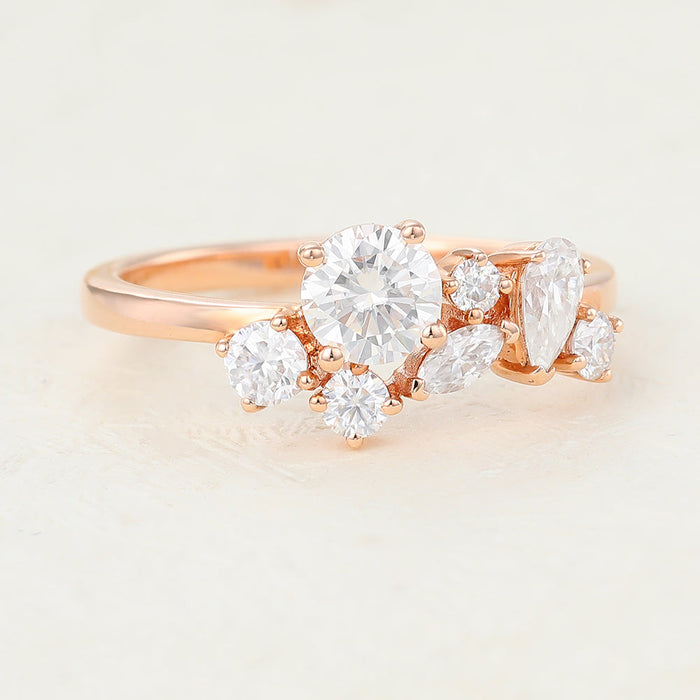 Rose gold moissanite cluster band with a round stone, marquise, pear and small round stones, angled view