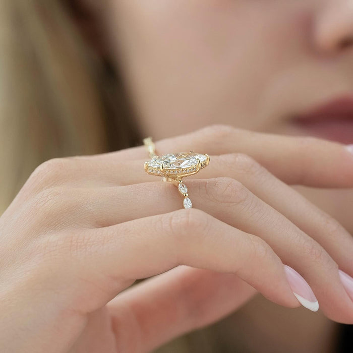 Marquise moissanite ring with spaced marquise accent band held in fingers in yellow gold
