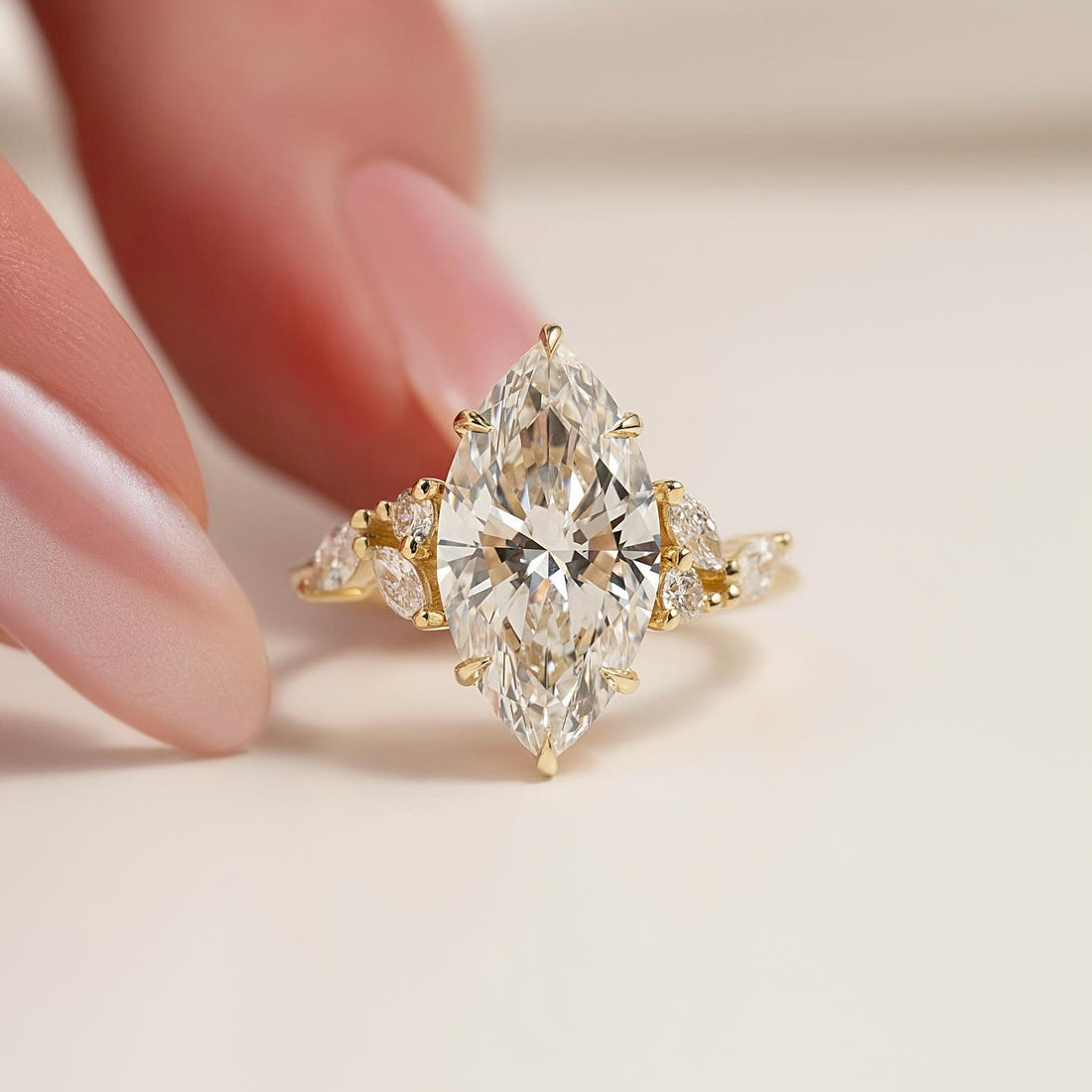 Marquise moissanite petal cluster accent ring held in fingers in yellow gold