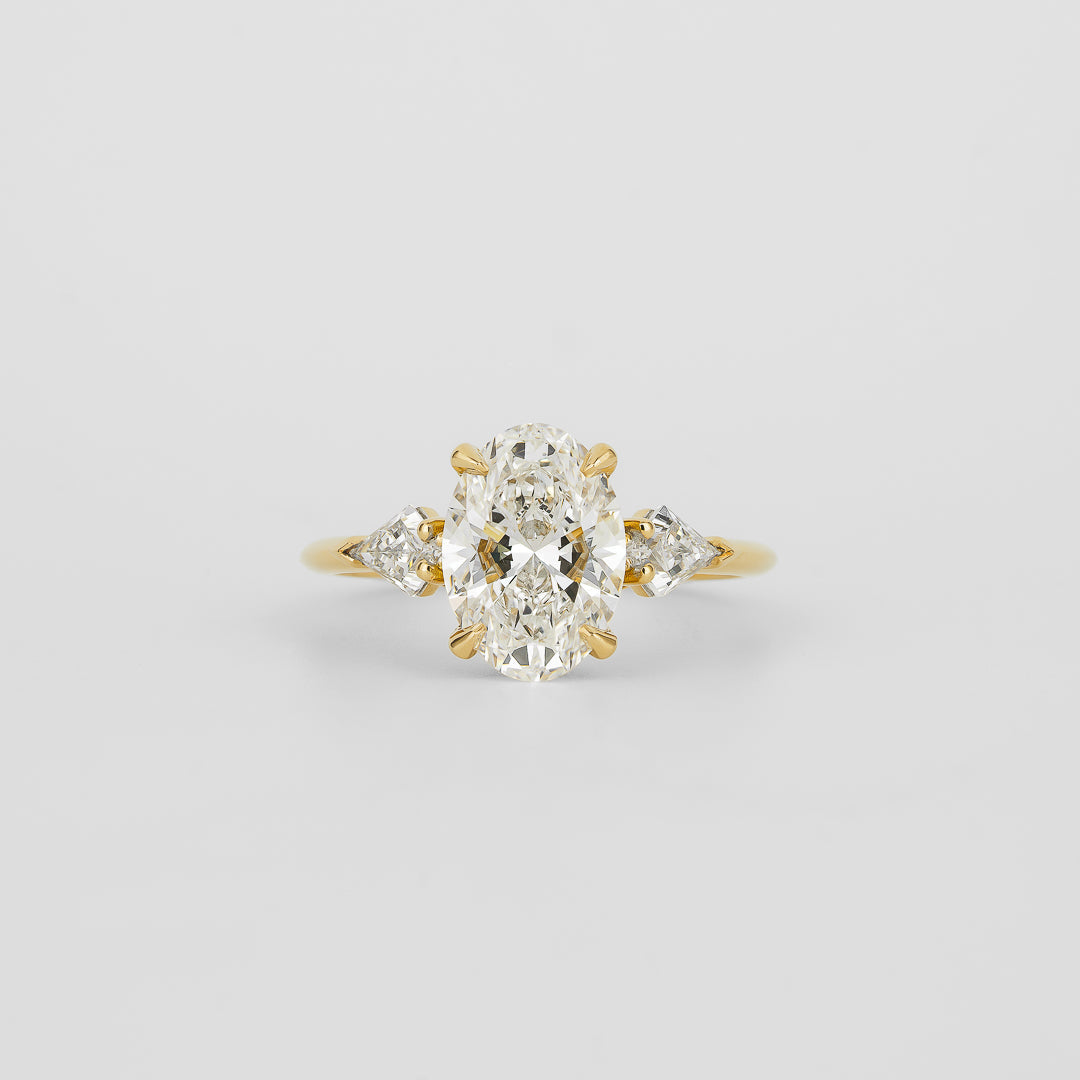 Oval cut lab grown diamond three stone ring with kite cut side stones in yellow gold