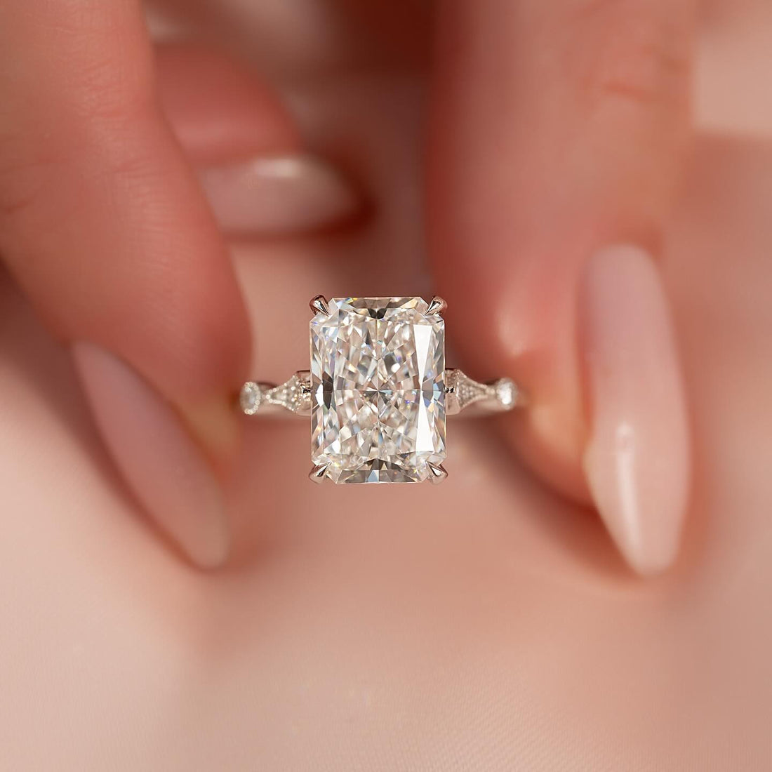 Radiant cut moissanite hidden halo vintage band ring held in fingers in white gold