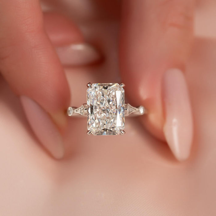 Radiant cut moissanite hidden halo vintage band ring held in fingers in white gold