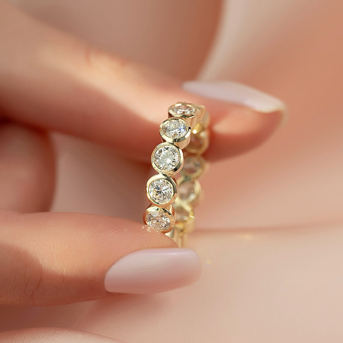Round moissanite bezel set full eternity band close up in yellow gold