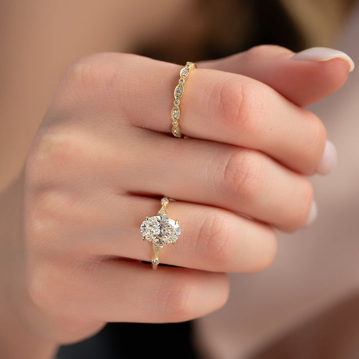 Oval moissanite vintage milgrain solitaire ring worn on hand in yellow gold