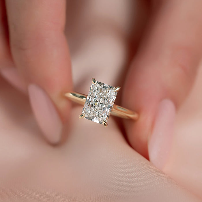 Radiant cut moissanite hidden halo plain band ring close up in yellow gold